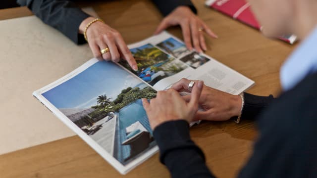 Katalog mit Reisebildern, Hände, die etwas darin zeigen. Katalog mit Reisebildern, Hände, die etwas darin zeigen.
