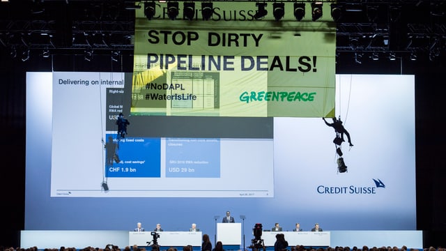 Activists da Greenpeace sa laschan giu vi d'ina suga durant la radunanza generala da la CS. Activists da Greenpeace sa laschan giu vi d'ina suga durant la radunanza generala da la CS.