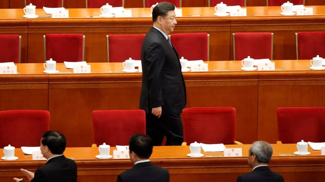 Xi zwischen den roten Sitzreihen des Volkskongresses. Xi zwischen den roten Sitzreihen des Volkskongresses.