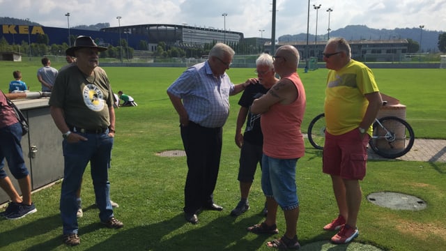 Vier ältere Herren stehen am Rend des Spielfelds, diskutieren, klopfen sich auf die Schulter Vier ältere Herren stehen am Rend des Spielfelds, diskutieren, klopfen sich auf die Schulter