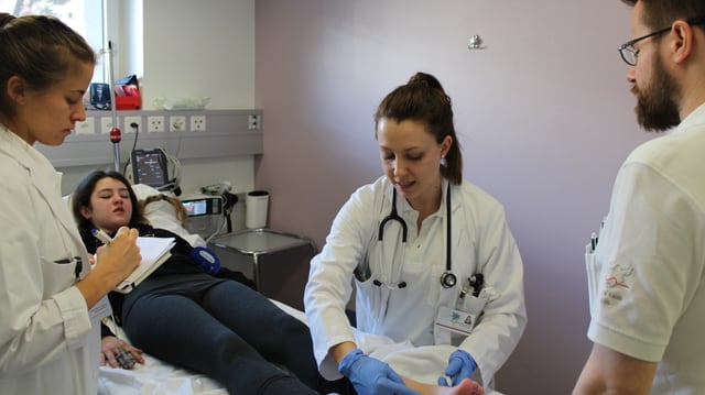 Ärzte mit einer Patientin, die auf dem Bett liegt. Ärzte mit einer Patientin, die auf dem Bett liegt.
