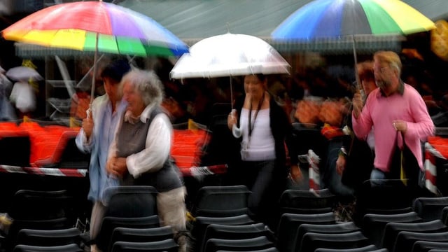 Menschen mit bunten Regenschirmen auf Tribüne. Menschen mit bunten Regenschirmen auf Tribüne.