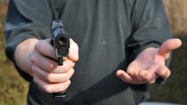 Ein Mann hält eine Pistole in der Hand Ein Mann hält eine Pistole in der Hand