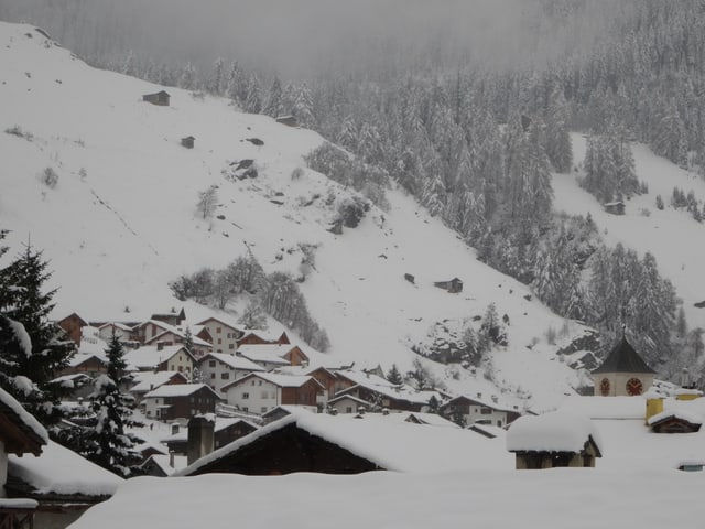 Die Dächer von Vals sind mit Neuschnee bedeckt. Auch der Hang an der anderen Talseite ist weiss.