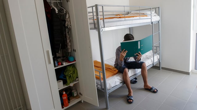 Ein Mann sitzt auf einem Doppelbett und liest Ein Mann sitzt auf einem Doppelbett und liest