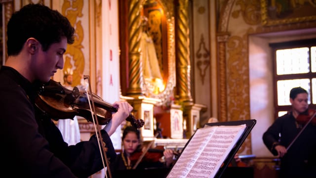 Ein junger Mann spielt in einer Kirche Violine.