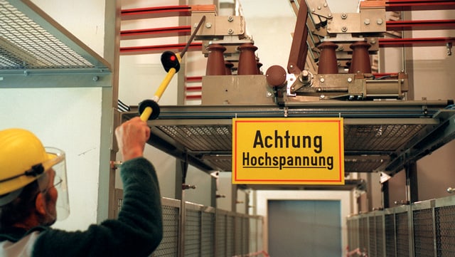 Ein Arbeiter misst mit einem Stab wohl die Spannung in einer Trafostation eines Elektrizitätswerkes. Ein Arbeiter misst mit einem Stab wohl die Spannung in einer Trafostation eines Elektrizitätswerkes.