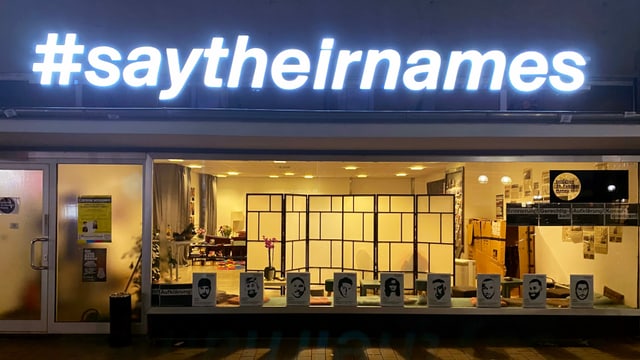 ein Neon-Schild, welches an einem Gebäude hängt und sagt: Say their names ein Neon-Schild, welches an einem Gebäude hängt und sagt: Say their names