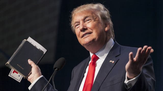 Trump hält während einer Rede eine Bibel in die Luft. Trump hält während einer Rede eine Bibel in die Luft.