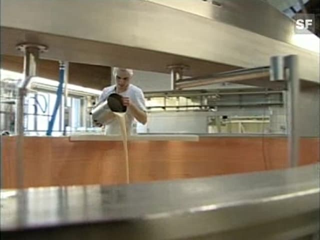 Ein in weiss gekleideter Mann giesst aus einem Stahleimer eine Flüssigkeit aus.