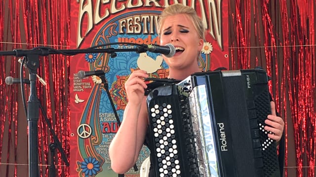 Eine Frau mit Akkordeon singt in eine Mikrophon Eine Frau mit Akkordeon singt in eine Mikrophon