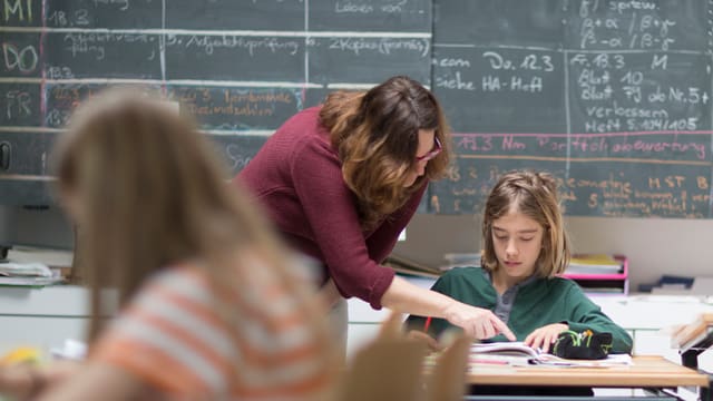 Lehrerin erklärt einer Schülerin Aufgaben vor einer Wandtafel Lehrerin erklärt einer Schülerin Aufgaben vor einer Wandtafel