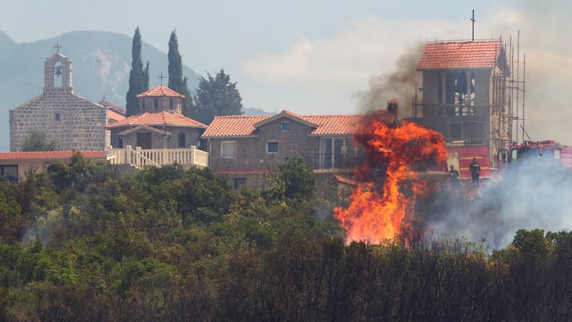 Feuer im Vordergrund, im Hintergrund ein Haus. Feuer im Vordergrund, im Hintergrund ein Haus.