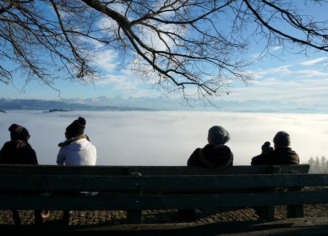 Vier Menschen hocken auf der Bank an der Sonne und schauen auf das Nebelmeer. Vier Menschen hocken auf der Bank an der Sonne und schauen auf das Nebelmeer.