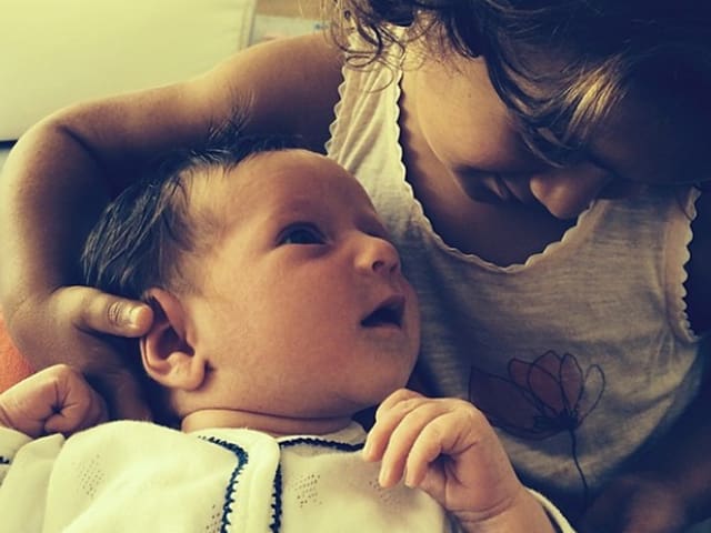 Ein Mädchen hält ein Baby im Arm und hält sein Köpfchen. Ein Mädchen hält ein Baby im Arm und hält sein Köpfchen.