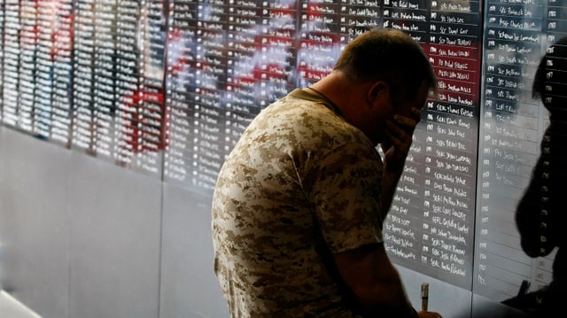 Ein Soldat kniet vor einer Wand, auf der Namen von gefallenen Kollegen stehen.