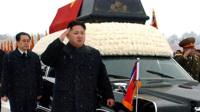 Kim Jong Un salutierend neben dem Sarg seines Vater. Im Hintergrund Jang Song Thaek. Kim Jong Un salutierend neben dem Sarg seines Vater. Im Hintergrund Jang Song Thaek.
