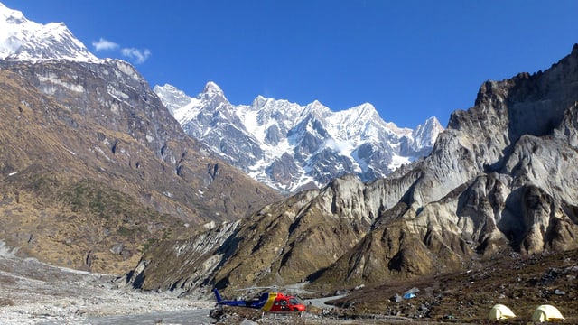 Ein Hubschrauber und zwei Zelte vor einer mächtigen, aber gletscherlosen Bergkulisse im Himalaja. Ein Hubschrauber und zwei Zelte vor einer mächtigen, aber gletscherlosen Bergkulisse im Himalaja.