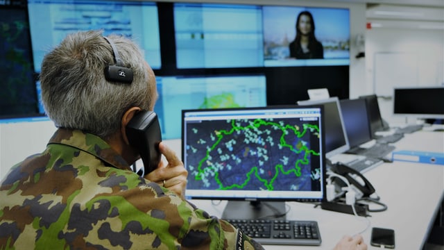 Telefonierender Mann am Computer. Vor sich auf dem Bildschirm eine Schweizer Karte. Telefonierender Mann am Computer. Vor sich auf dem Bildschirm eine Schweizer Karte.
