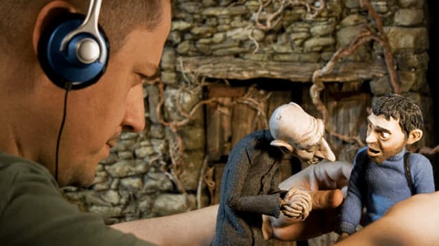 Ein Filmemacher bewegt mit den Händen zwei Filmfiguren. Ein Filmemacher bewegt mit den Händen zwei Filmfiguren.