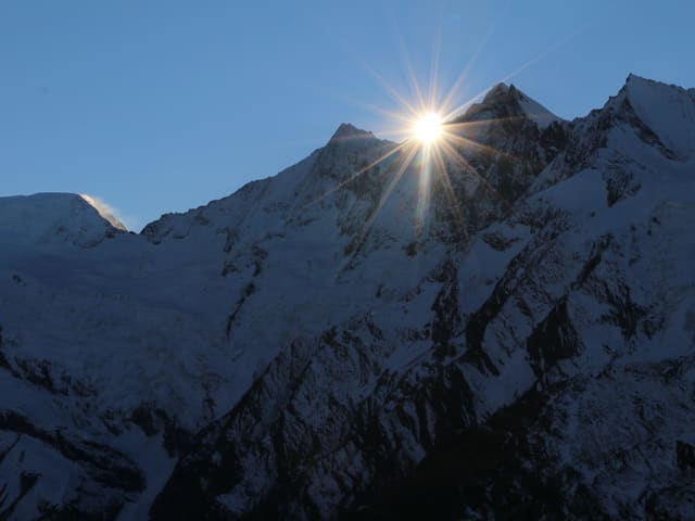 Eine verglescherte Bergwelt mit dem Wind der über die besonnte Krete bläst. Darüber tiefblauer Himmel.