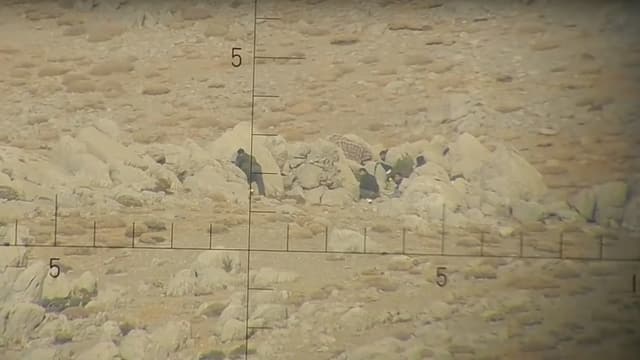 Blick durch das Fernrohr mit Fadenkreuz auf die Männer in den Felsen. Blick durch das Fernrohr mit Fadenkreuz auf die Männer in den Felsen.