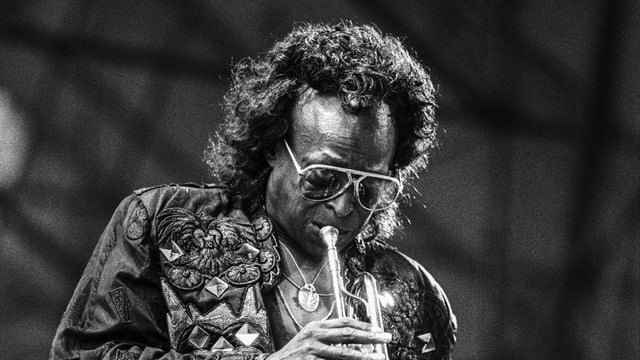 Eine Schwarzweiss-Aufnahme von Miles Davis, Trompete spielend Eine Schwarzweiss-Aufnahme von Miles Davis, Trompete spielend