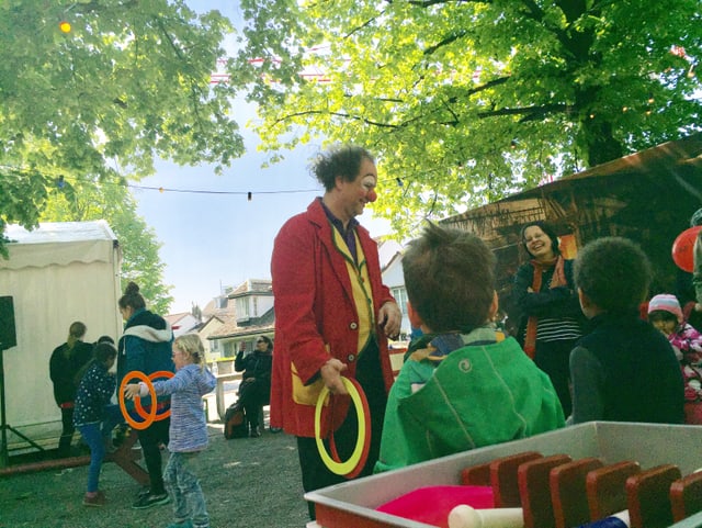 Ein Mann in roter Clownsjacke, davor viele Kinder Ein Mann in roter Clownsjacke, davor viele Kinder