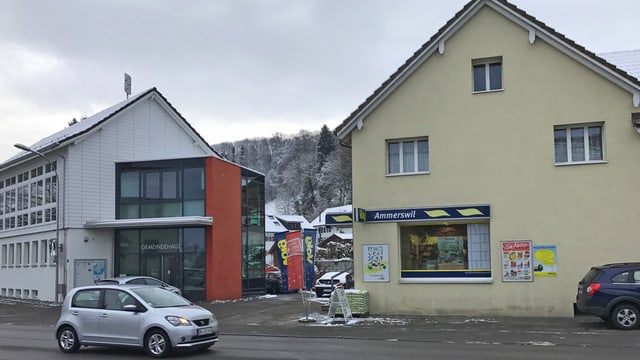 Ein weisses Haus mit Glas und ein gelbes Haus stehen nebeneinander, davor stehen 2 Autos. Ein weisses Haus mit Glas und ein gelbes Haus stehen nebeneinander, davor stehen 2 Autos.
