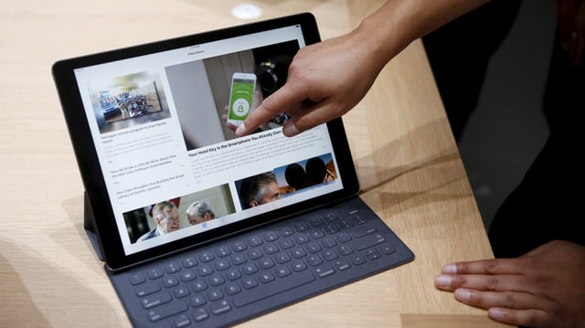 Eine Hand zeigt auf das neue iPad Pro, das in seiner Tastatur-Hülle steckt. Eine Hand zeigt auf das neue iPad Pro, das in seiner Tastatur-Hülle steckt.