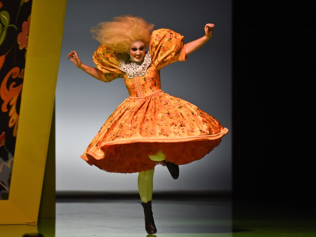 Eine Frau in einem orangen Kleid, knielang, ausgestellt - mit orangen Haaren. Eine Frau in einem orangen Kleid, knielang, ausgestellt - mit orangen Haaren.