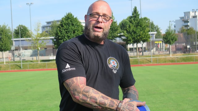 Ein Mann steht mit einem Diskus auf einem Sportplatz. Ein Mann steht mit einem Diskus auf einem Sportplatz.