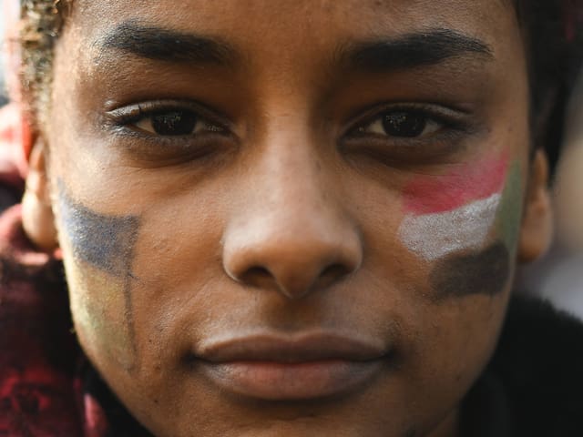 Frau mit aufgemalter sudanesischer Flagge auf der Wange Frau mit aufgemalter sudanesischer Flagge auf der Wange