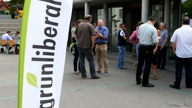 Ein paar Leute stehen vor einem Gebäude, eine Fahne der Grünliberalen davor (Parteitag Juni 2014). Ein paar Leute stehen vor einem Gebäude, eine Fahne der Grünliberalen davor (Parteitag Juni 2014).