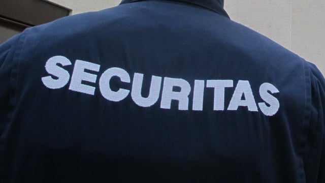 Rückenansicht eines Securitas-Mitarbeiters, auf dem Rücken seiner Uniform ist das Firmenlogo zu sehen. Rückenansicht eines Securitas-Mitarbeiters, auf dem Rücken seiner Uniform ist das Firmenlogo zu sehen.