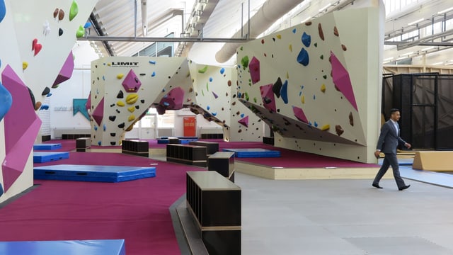 Eine Halle mit Kletterwänden und Matten auf dem Boden. Eine Halle mit Kletterwänden und Matten auf dem Boden.