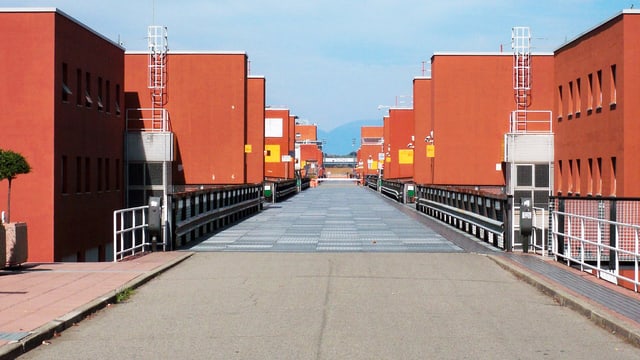 Ein Weg, der zwischen zweistöckigen, orangen Häusern hindurch führt. Ein Weg, der zwischen zweistöckigen, orangen Häusern hindurch führt.
