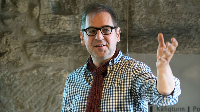 Daniel Howald auf einer Bühne. Er trägt Hemd und Brille. Daniel Howald auf einer Bühne. Er trägt Hemd und Brille.