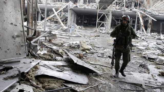 Bewaffneter Separatist geht durch Trümmer