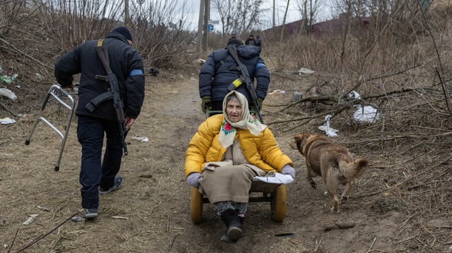 Ukrainische Soldaten evakuieren eine Frau aus der Stadt Irpin.