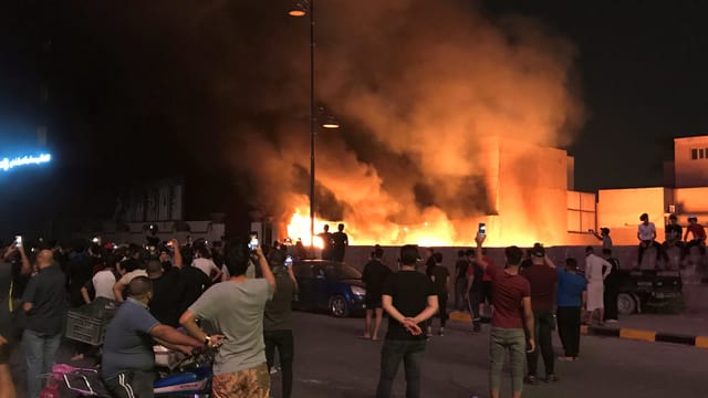 Protestierende stehen vor einem Brand in Bagdad. Protestierende stehen vor einem Brand in Bagdad.