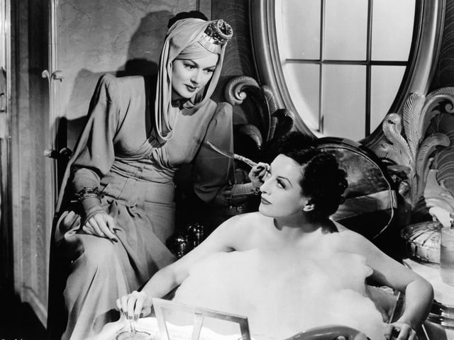 Zwei Frauen: eine sitzt auf einem Stuhl, die andere in der Badewanne. Zwei Frauen: eine sitzt auf einem Stuhl, die andere in der Badewanne.