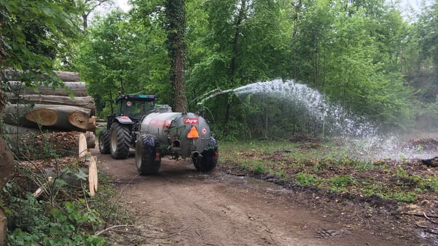Ein Jauchewagen im Wald bespritzt kleine Bäume mit Wasser. Ein Jauchewagen im Wald bespritzt kleine Bäume mit Wasser.