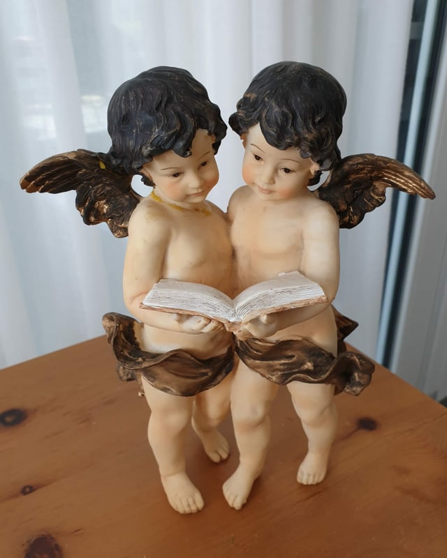 Zwei nackte Engel lesen Buch.