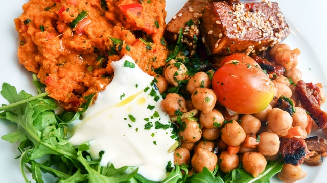 Ein Teller mit vegetarischen Zutaten wie zum Beispiel Tofu, Kichererbsen und Rucola. Ein Teller mit vegetarischen Zutaten wie zum Beispiel Tofu, Kichererbsen und Rucola.