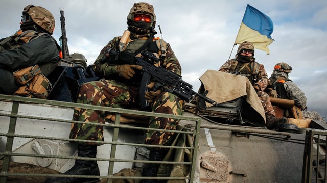 Ukrainische Soldaten sitzen bewaffnet auf einem Panzerfahrzeug. Ukrainische Soldaten sitzen bewaffnet auf einem Panzerfahrzeug.