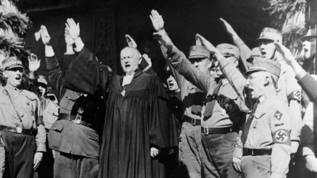 Ein Bischof inmitten von uniformierten Nazis. Alle machen den Hitlergruss Ein Bischof inmitten von uniformierten Nazis. Alle machen den Hitlergruss