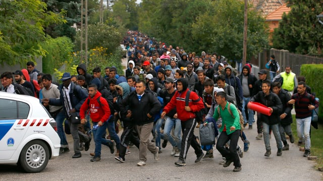 Flüchtlinge auf einer Strasse hinter einem Polizeiauto. Flüchtlinge auf einer Strasse hinter einem Polizeiauto.