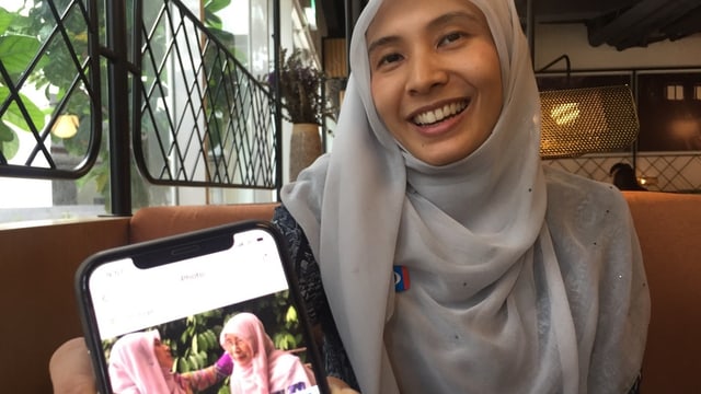 Nurul Izzah Anwar hält lächelnd ihr Smartphone in die Kamera Nurul Izzah Anwar hält lächelnd ihr Smartphone in die Kamera