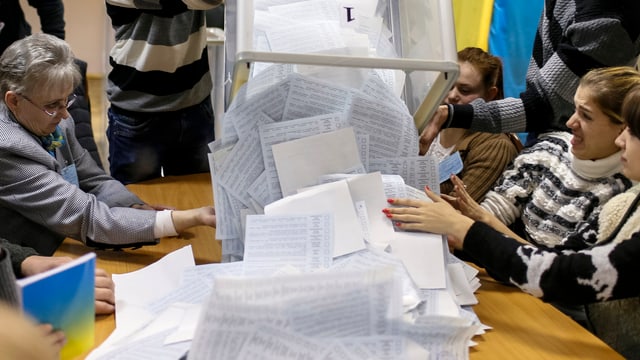 Wahlzettel werden aus einer Urne auf einen Tisch geleert. Wahlzettel werden aus einer Urne auf einen Tisch geleert.
